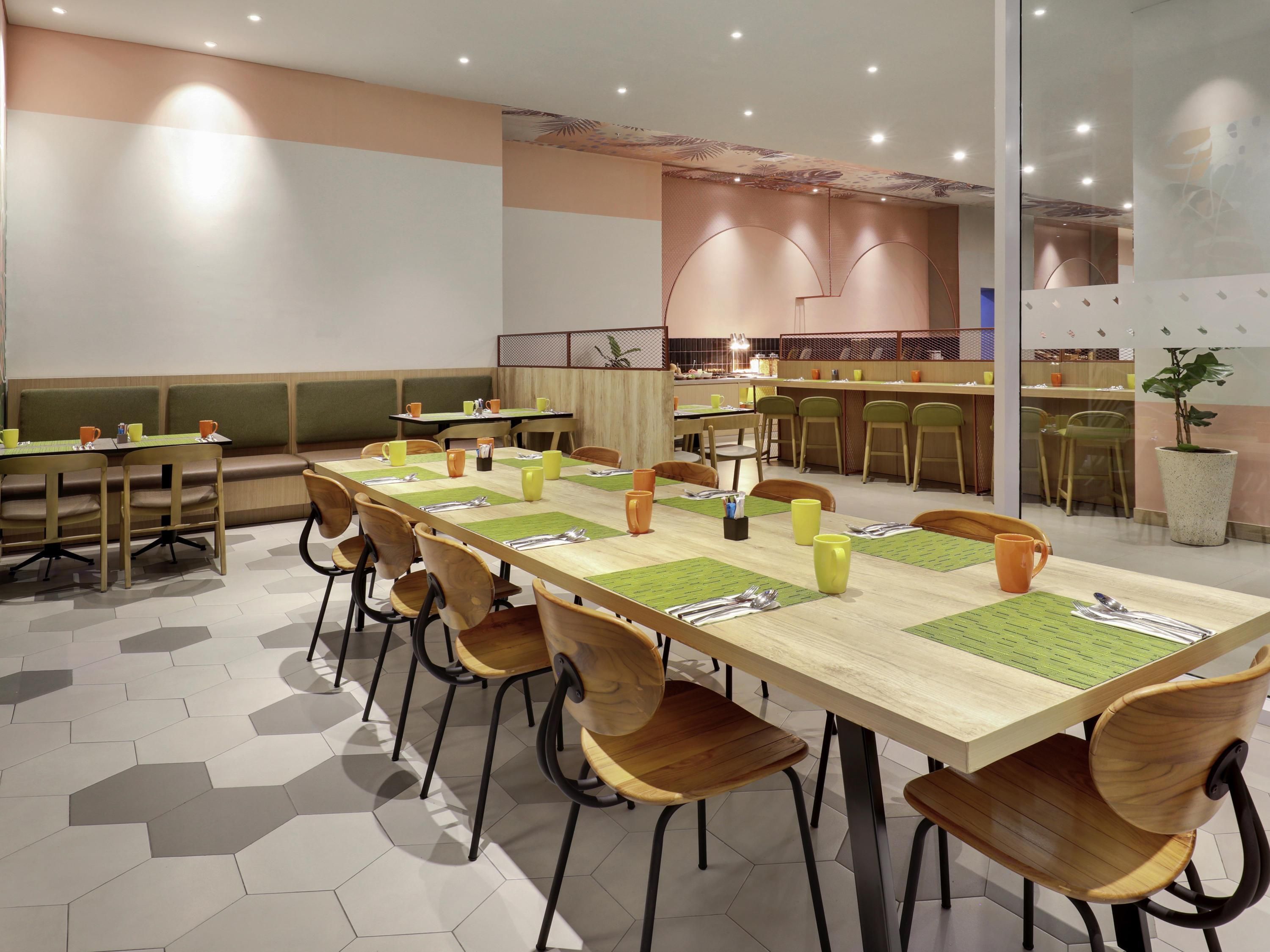 A modern dining area with long tables, chairs, and a bar counter.