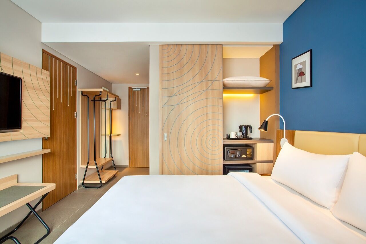A hotel room with a bed, a TV, a desk, and a wardrobe.