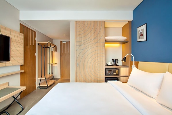 Habitación de hotel con cama, televisor, escritorio y armario.