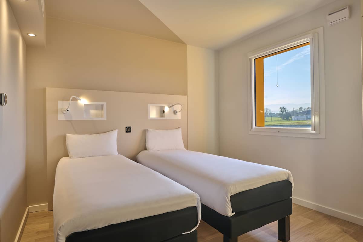 Ein Schlafzimmer mit zwei Betten, einem Fenster mit Blick und Wandleuchten.