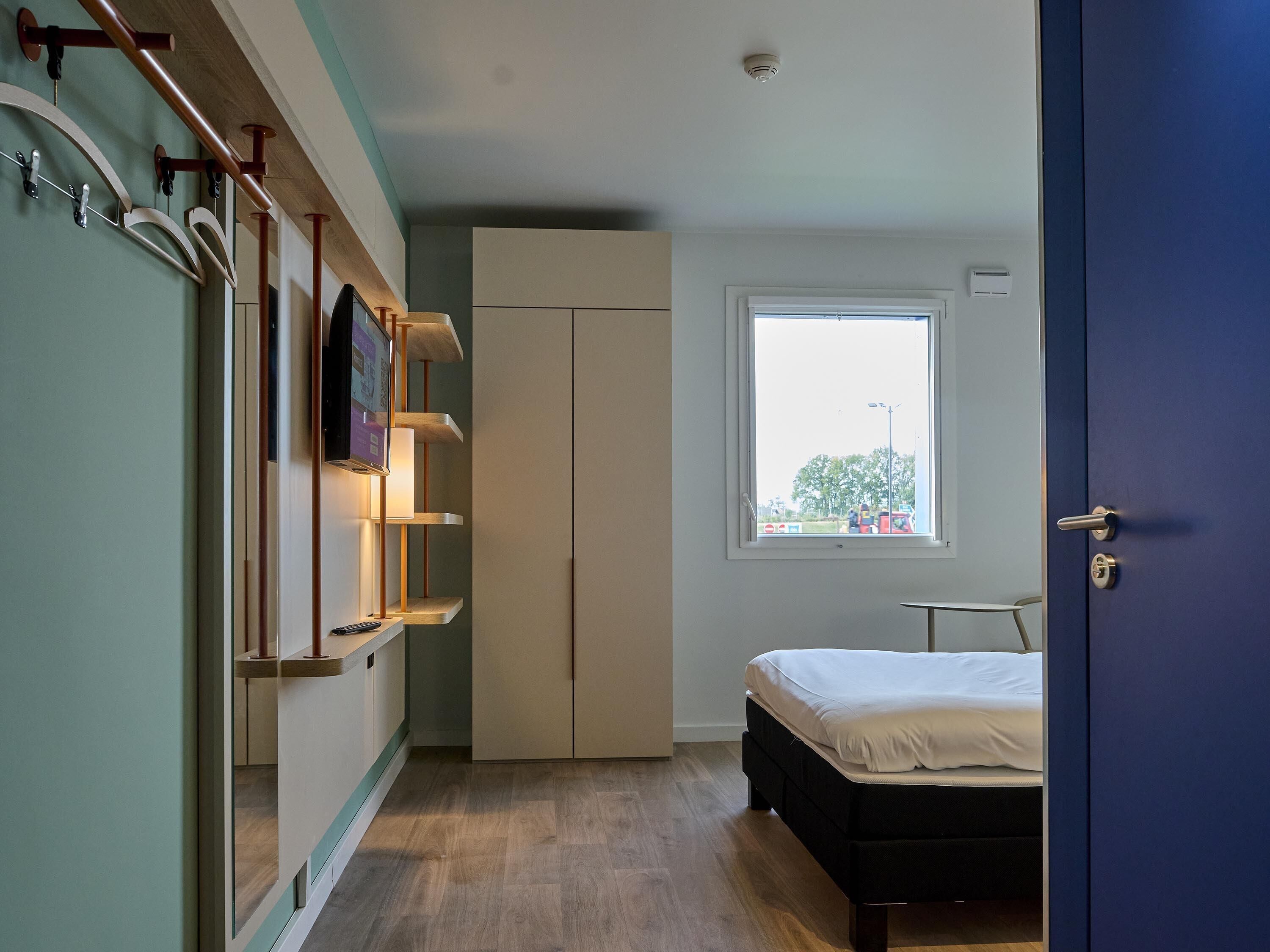 Un dormitorio con cama, armario, ventana y puerta.