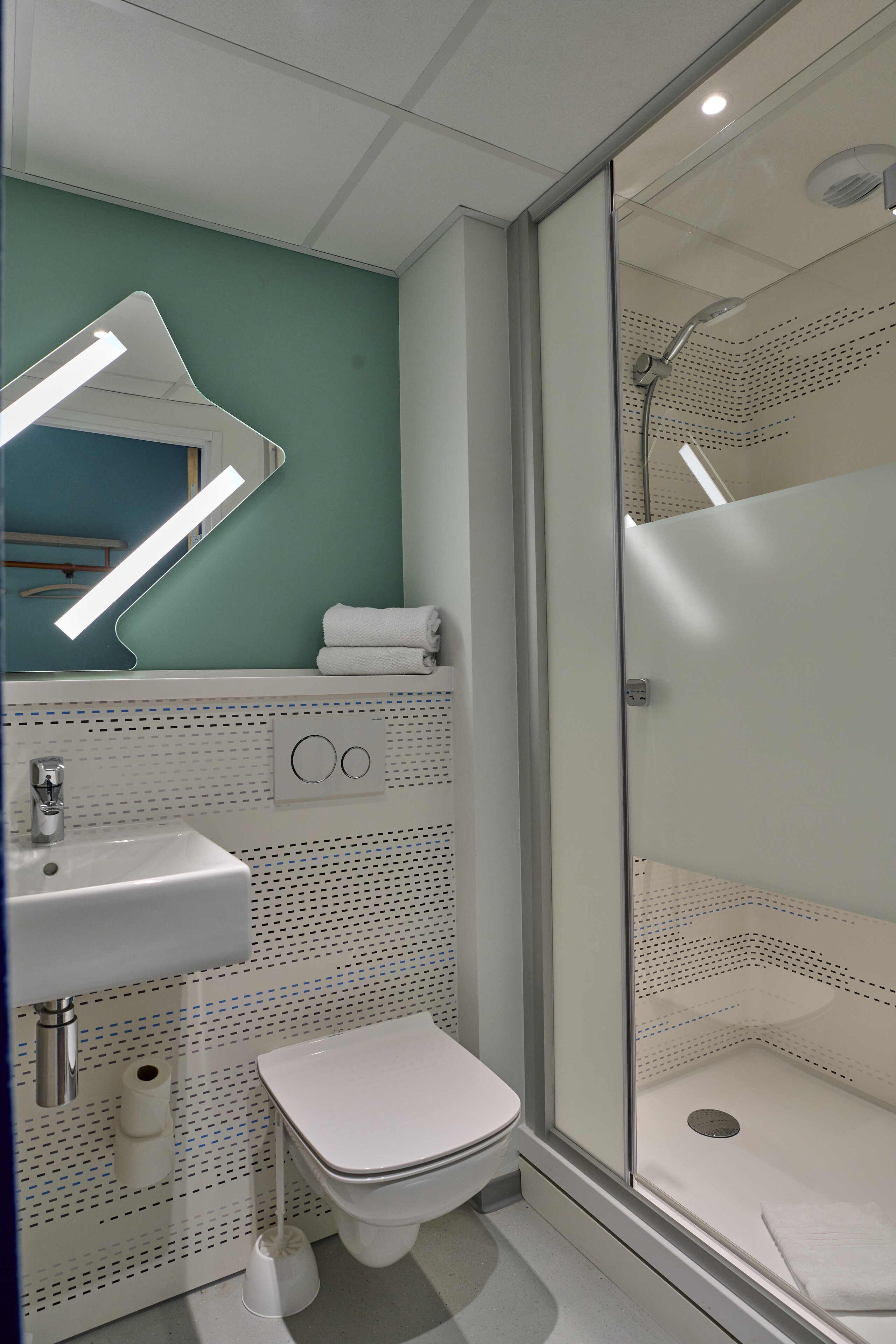 A bathroom with a white sink, toilet, and shower enclosure.