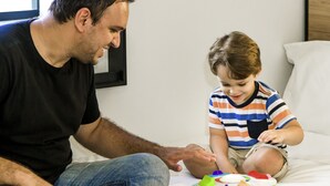 A man and a child on a bed with a baby activity center. - ibis Bethune Centre Gare (Béthune)