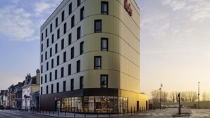 A modern hotel with a curved facade, multiple windows, and a visible entrance with glass doors. - ibis Bethune Centre Gare (Béthune)