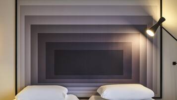 Una habitación de hotel con dos camas, una obra de arte grande enmarcada en la pared y una lámpara de noche.