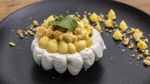A dessert on a black plate with crumbled topping and a green leaf garnish. - Mercure Bordeaux Centre Gare Atlantic (Bordeaux)