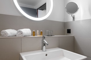 A modern bathroom with a white sink, two towels, and toiletries on the counter. - Mercure Bordeaux Centre Gare Atlantic (Bordeaux)