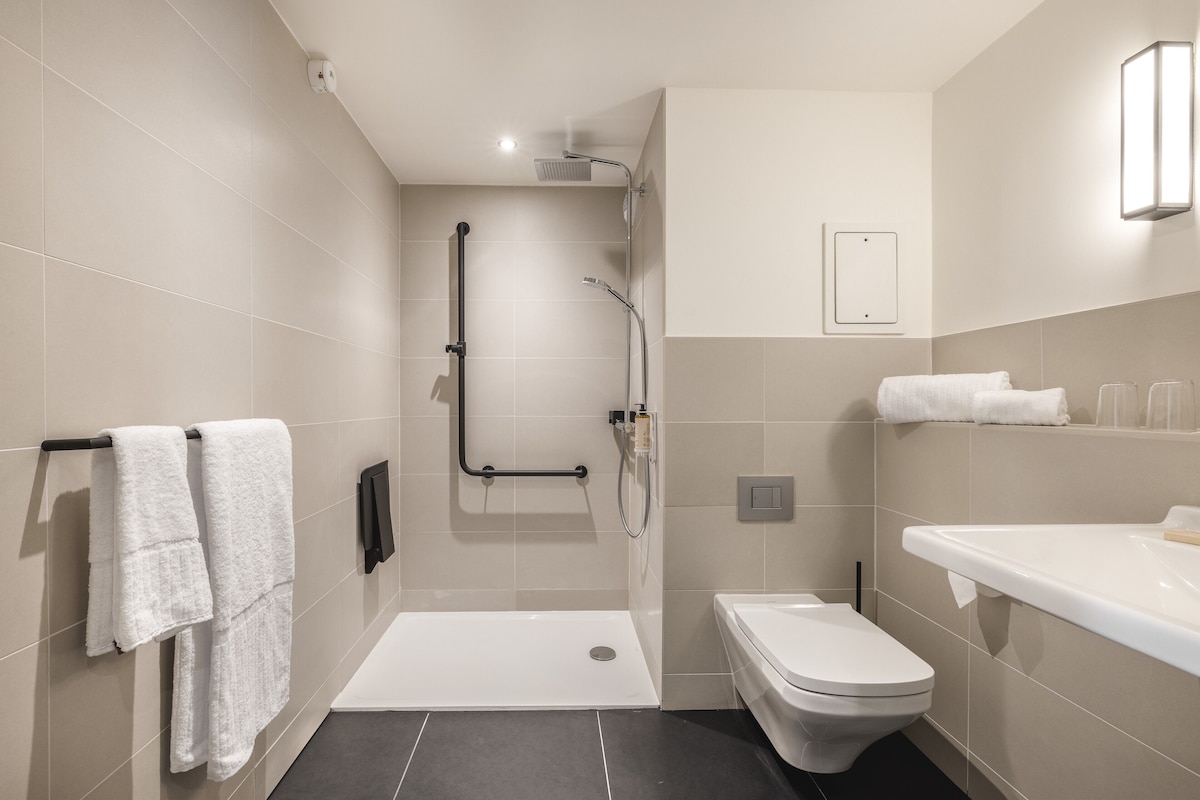 A modern bathroom with a shower, toilet, and sink.