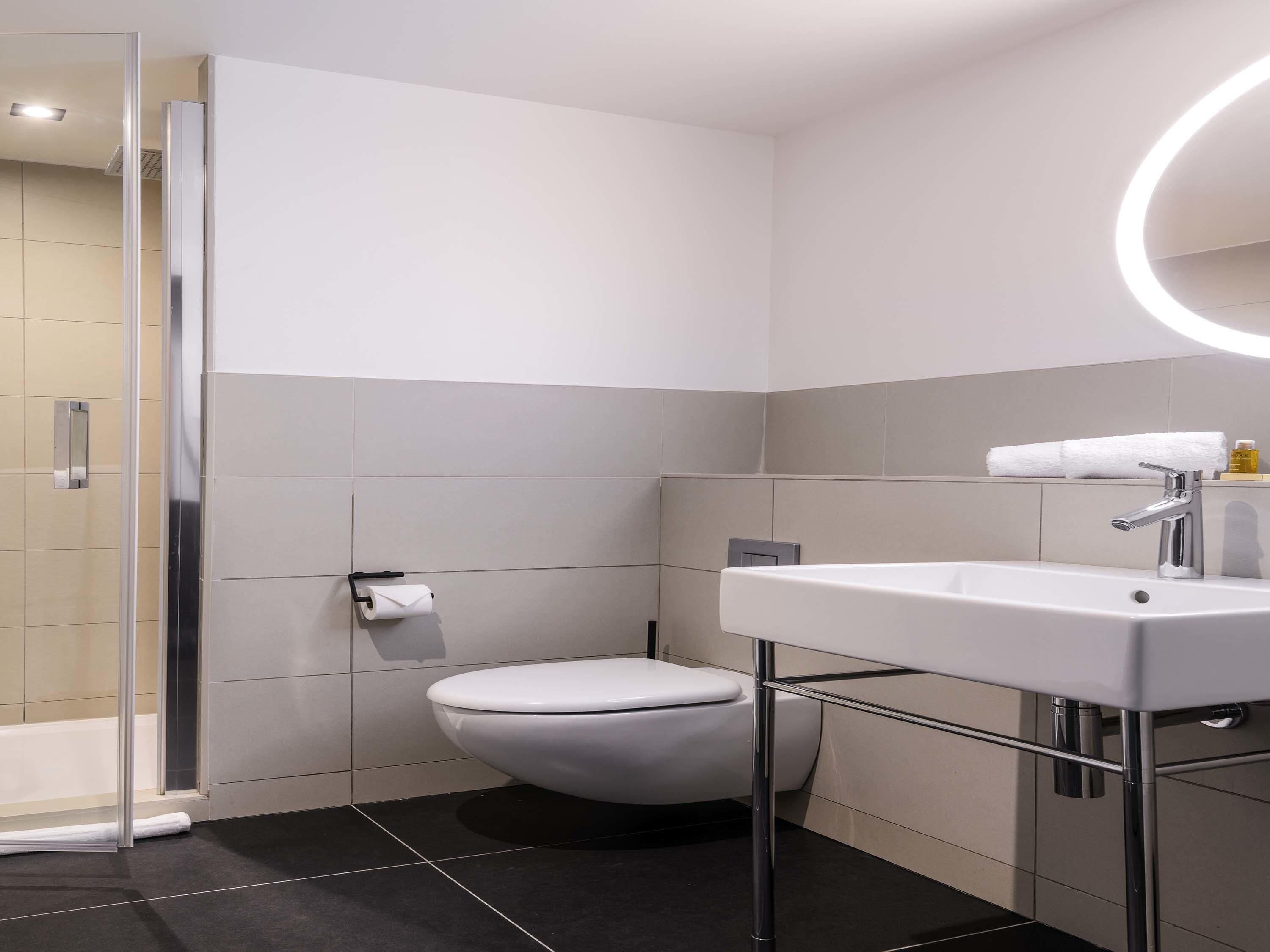 A modern bathroom with a toilet, sink, and shower area.