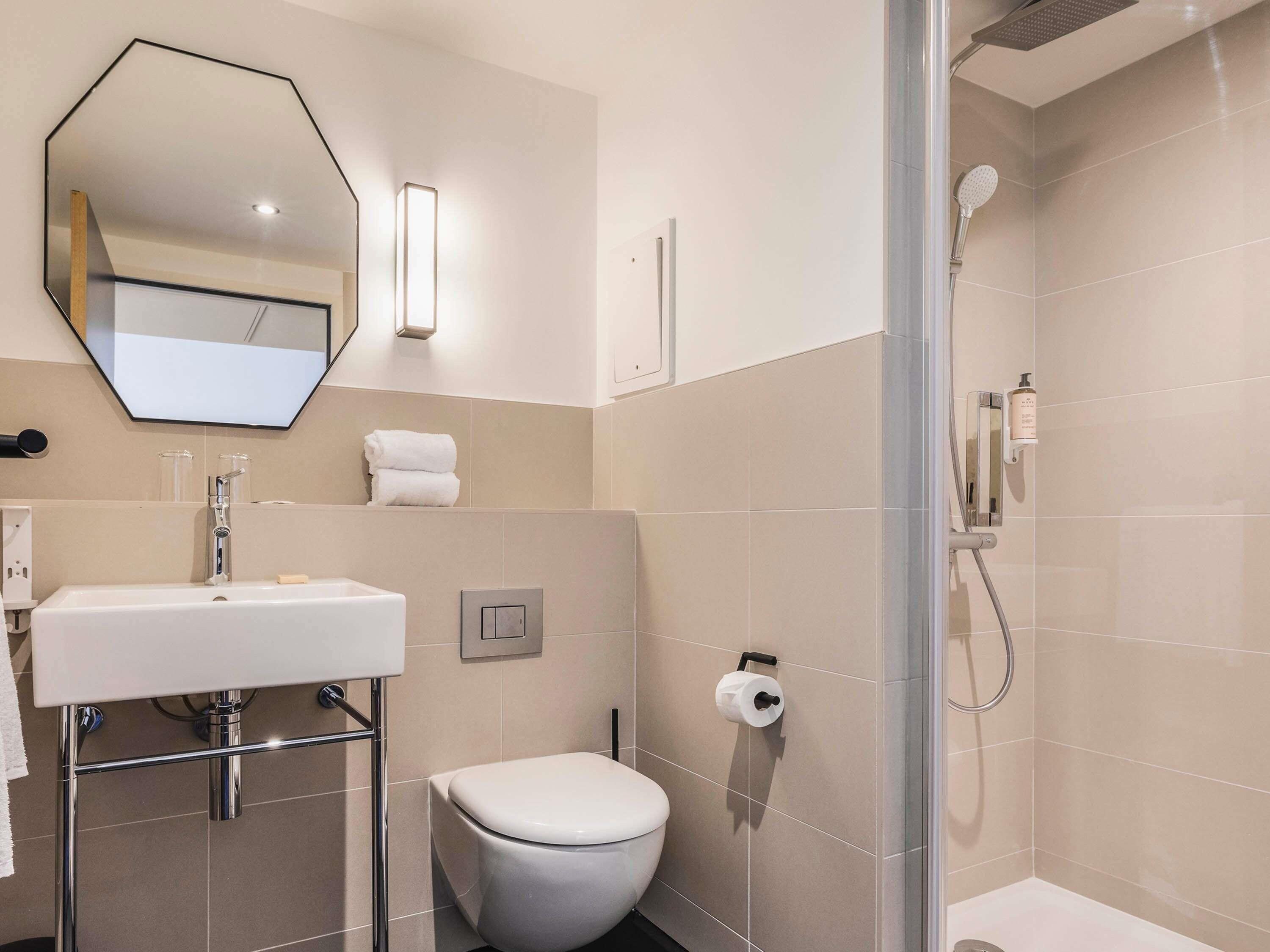 A modern bathroom with a white sink, toilet, and shower.
