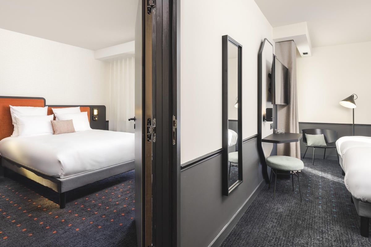 A hotel room with a bed, a desk, a chair, and a mirror.