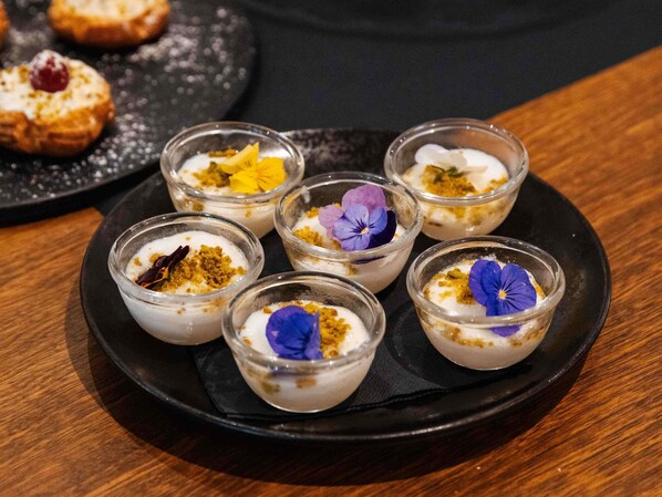 A dessert platter with six small glass cups, each containing a creamy dessert topped with a flower and crumbled topping. - Mercure Bordeaux Centre Gare Atlantic (Bordeaux)