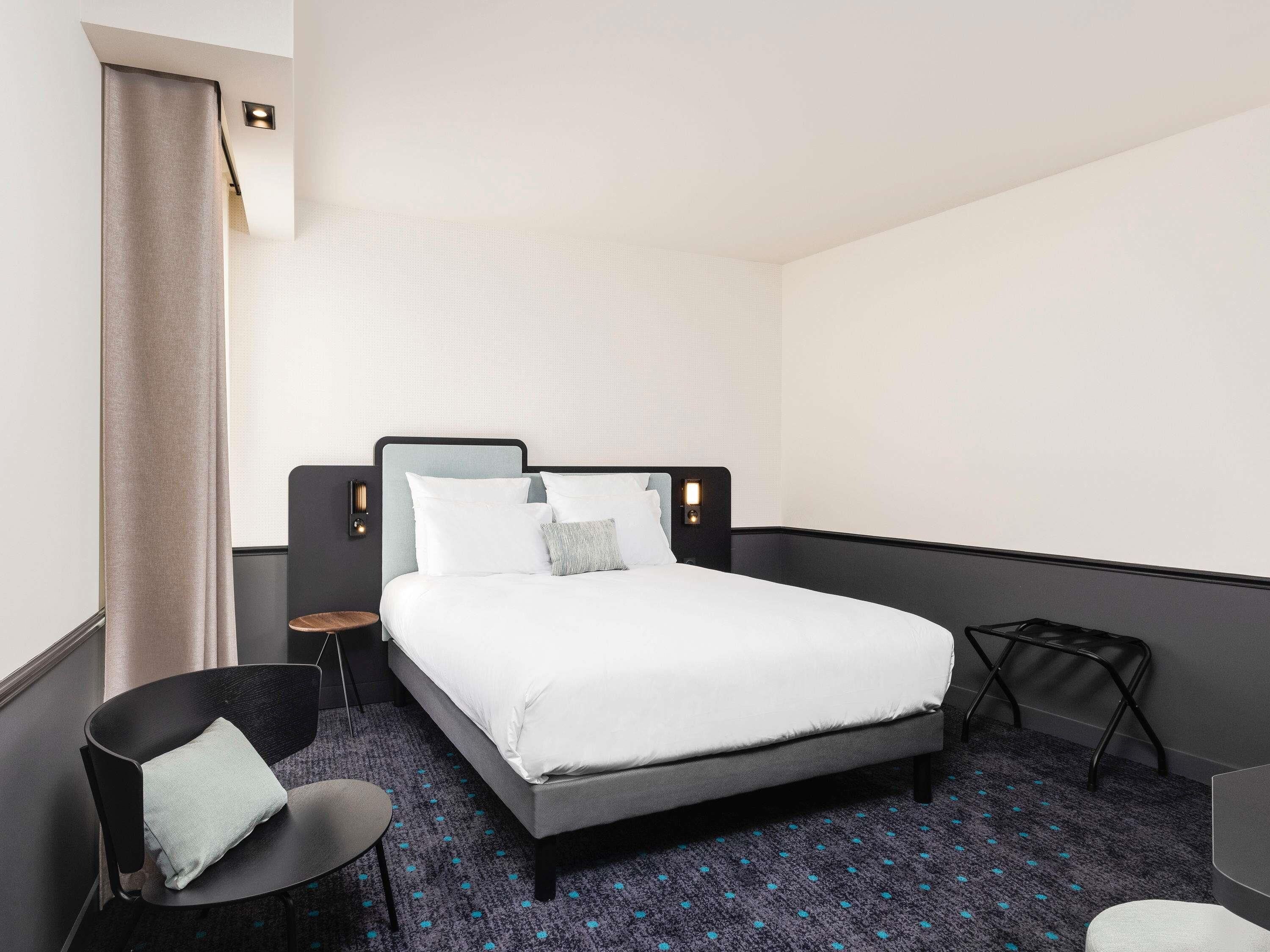 Une chambre d’hôtel moderne avec un grand lit, une petite table d’appoint, une chaise et un bureau.