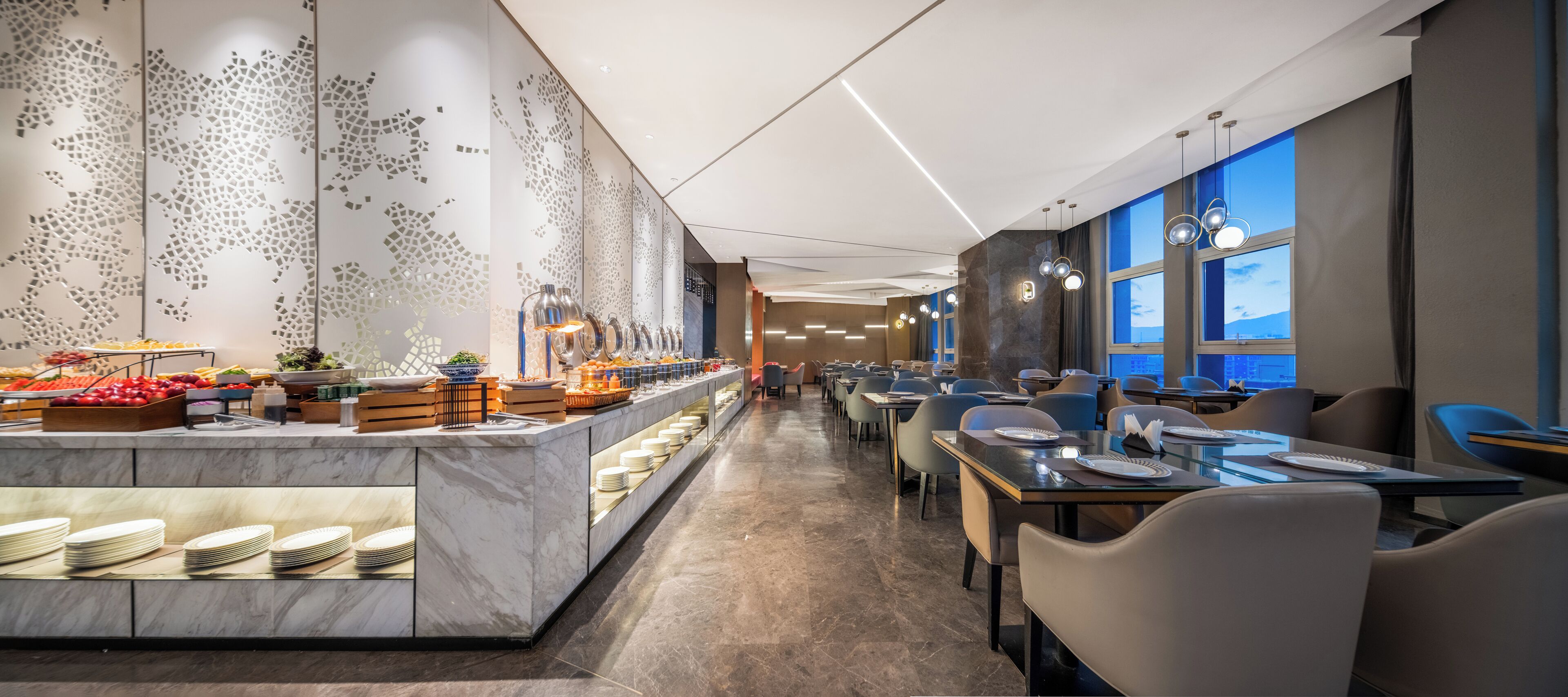 Un comedor de hotel moderno con una barra larga, bufé y disposición de mesas.