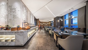 A modern hotel dining area with a long counter, buffet, and seating arrangement.