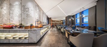 Un comedor de hotel moderno con una barra larga, bufé y disposición de mesas.