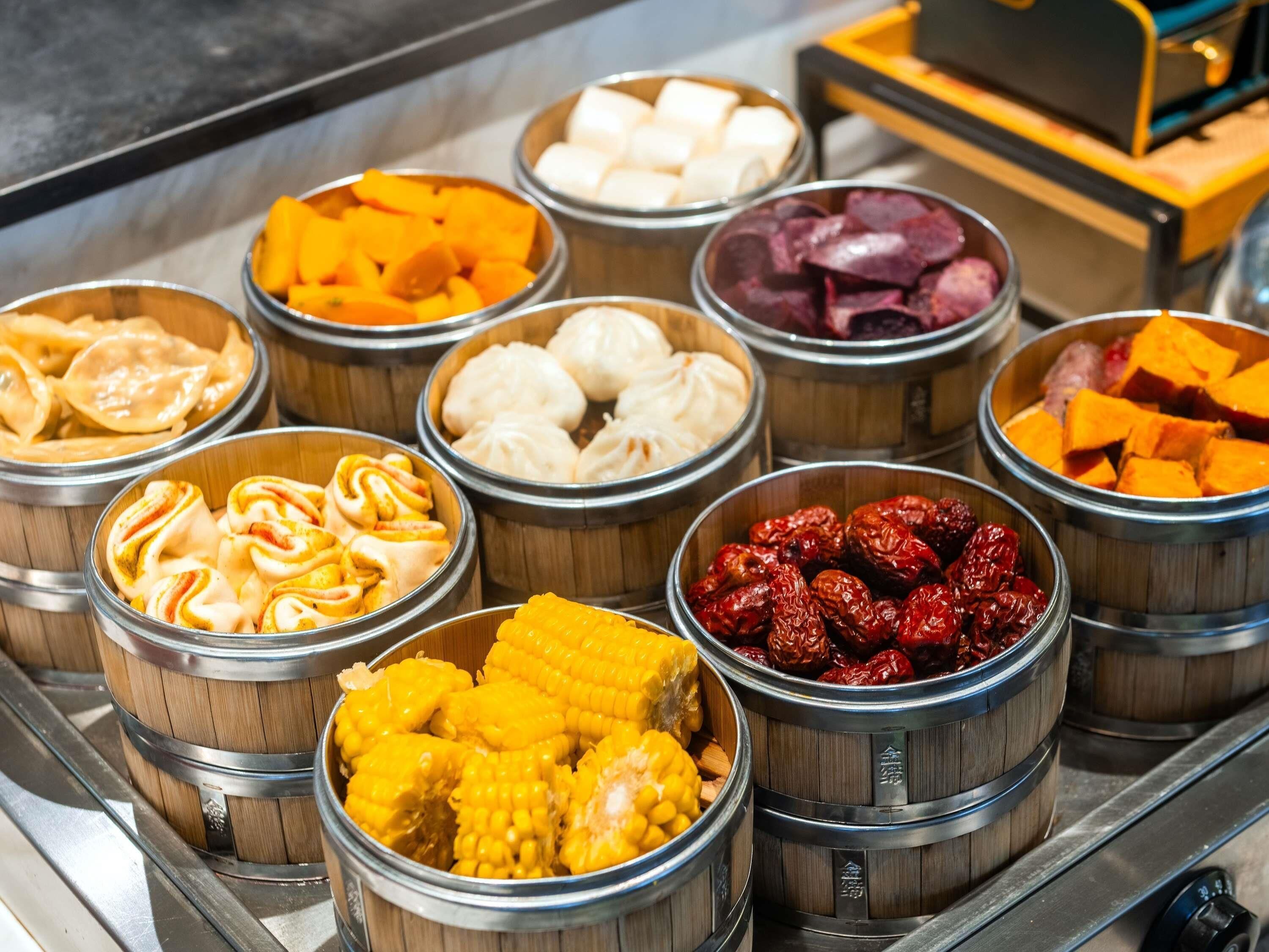 A buffet with various food items in bamboo steamers.