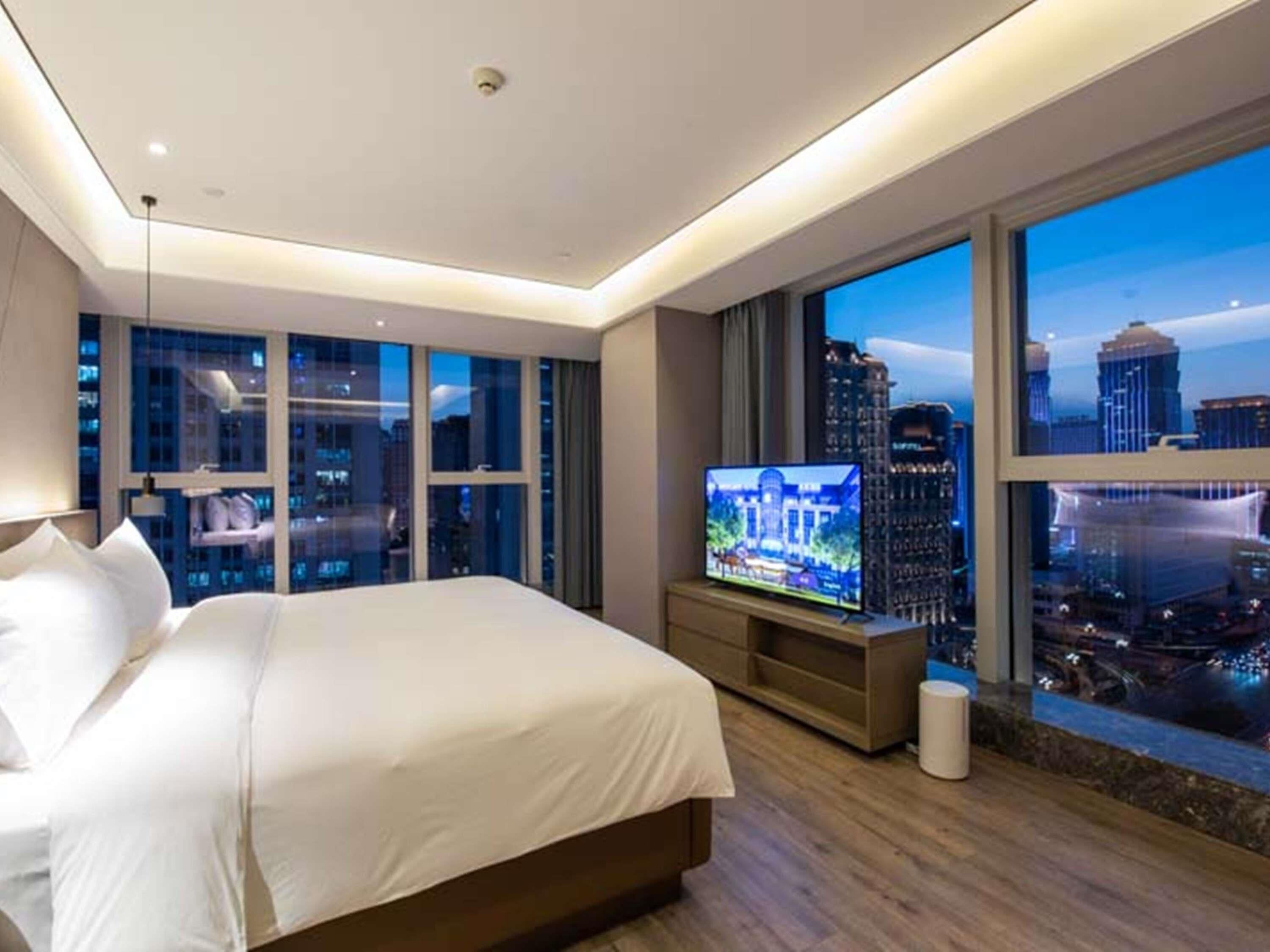 Una camera d'albergo con un letto grande, una televisione e vista sulla città.