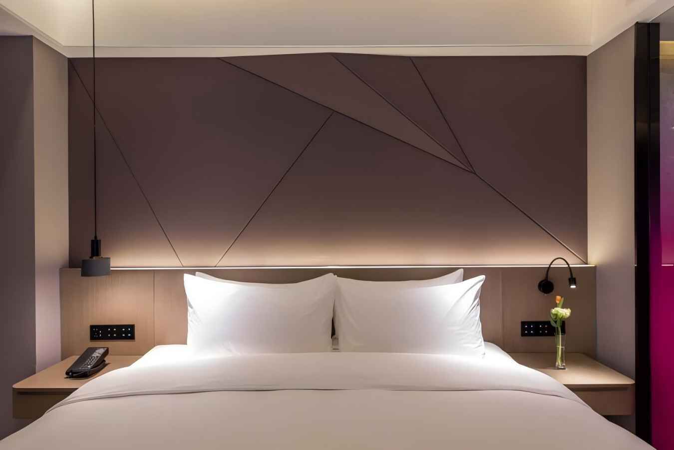 Ein modernes Hotelzimmer mit einem großen Bett, Nachttischen, einem Telefon und einer Lampe.