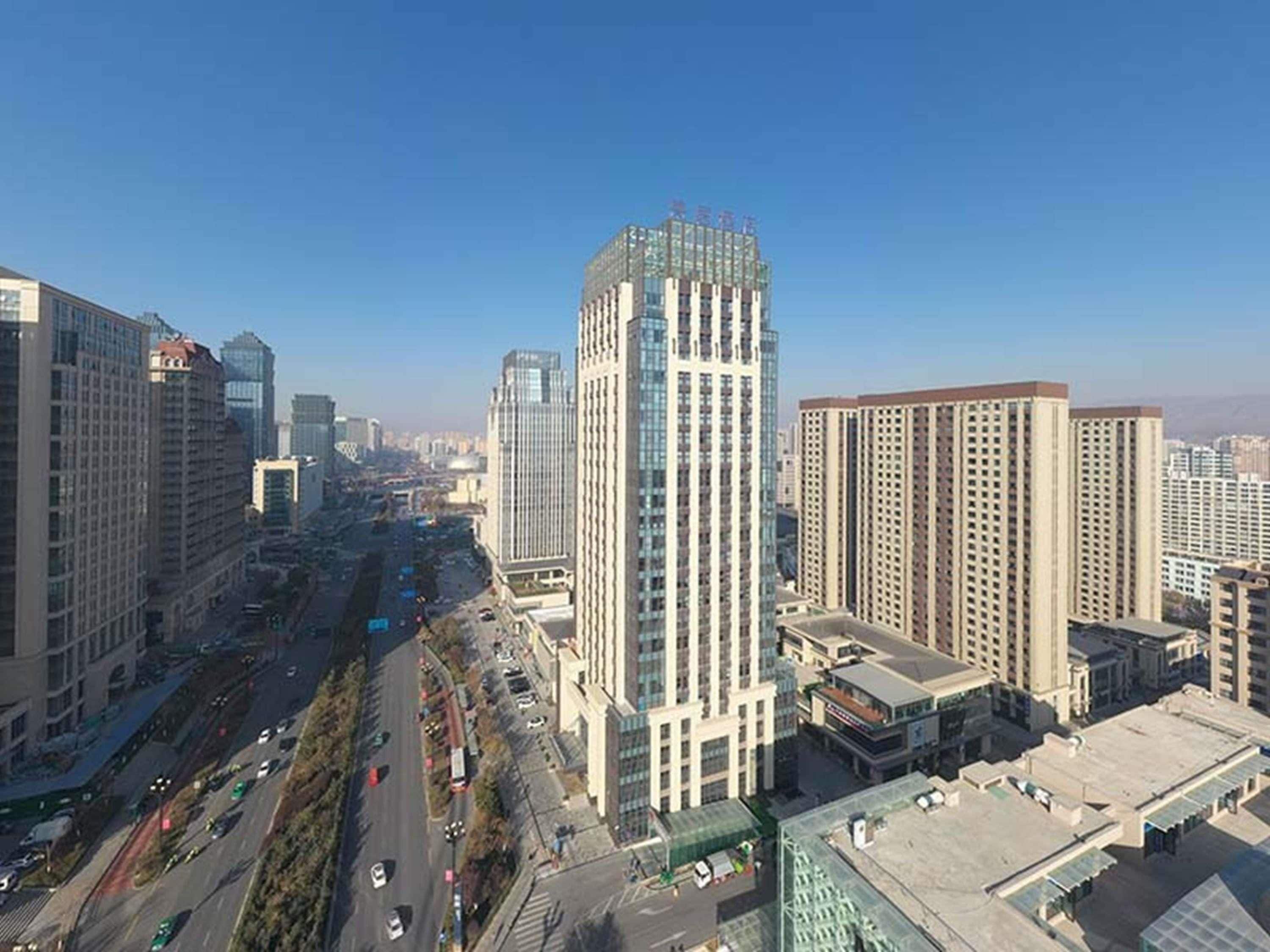A cityscape with high-rise buildings, a busy street, and a clear sky.