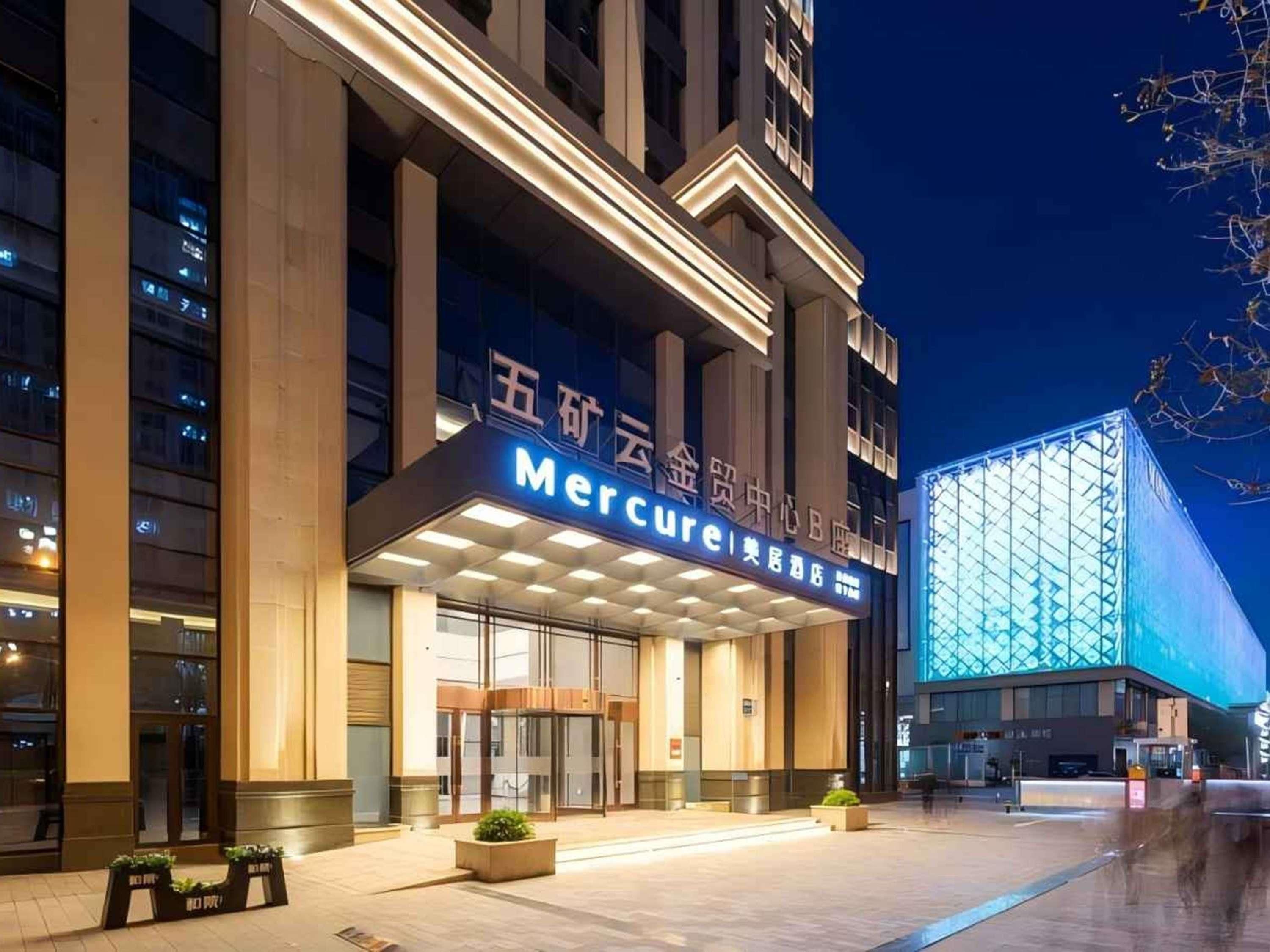 A hotel entrance with a prominent sign, large glass doors, and a modern building facade.