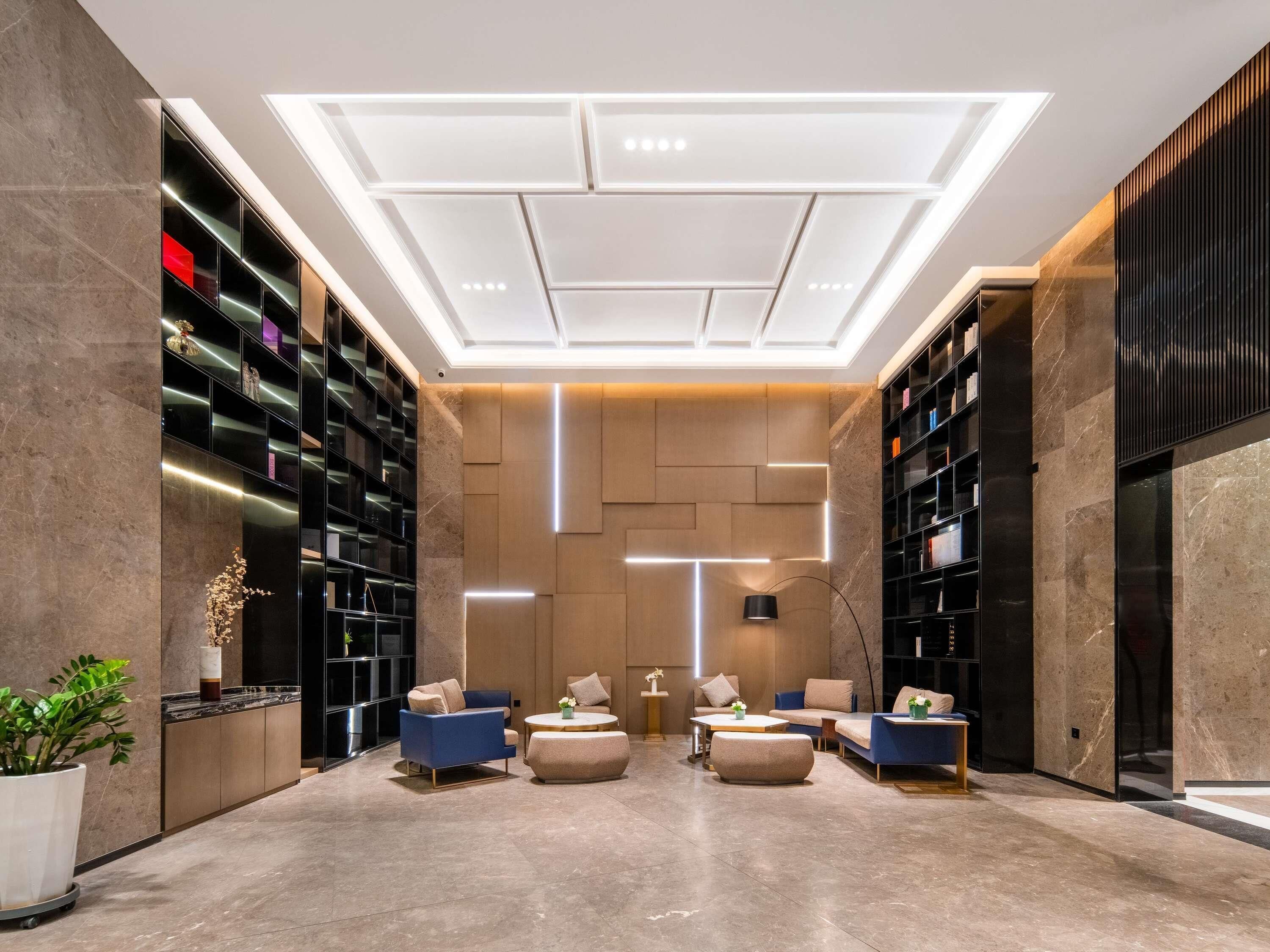 A modern interior with a central seating area, bookshelves, and a ceiling with recessed lighting.