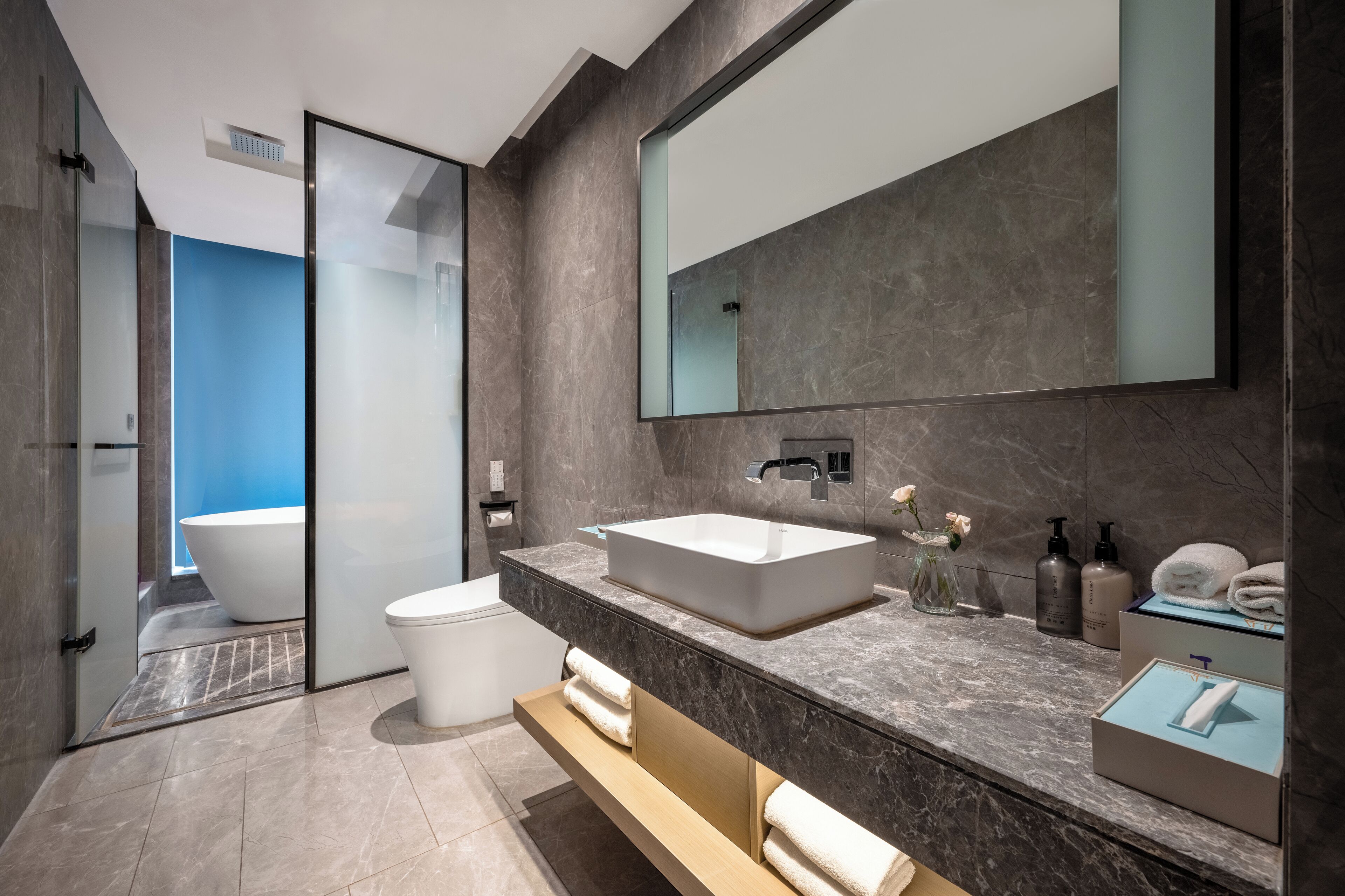 A modern bathroom with a large bathtub, a white sink, a mirror, and a towel rack.