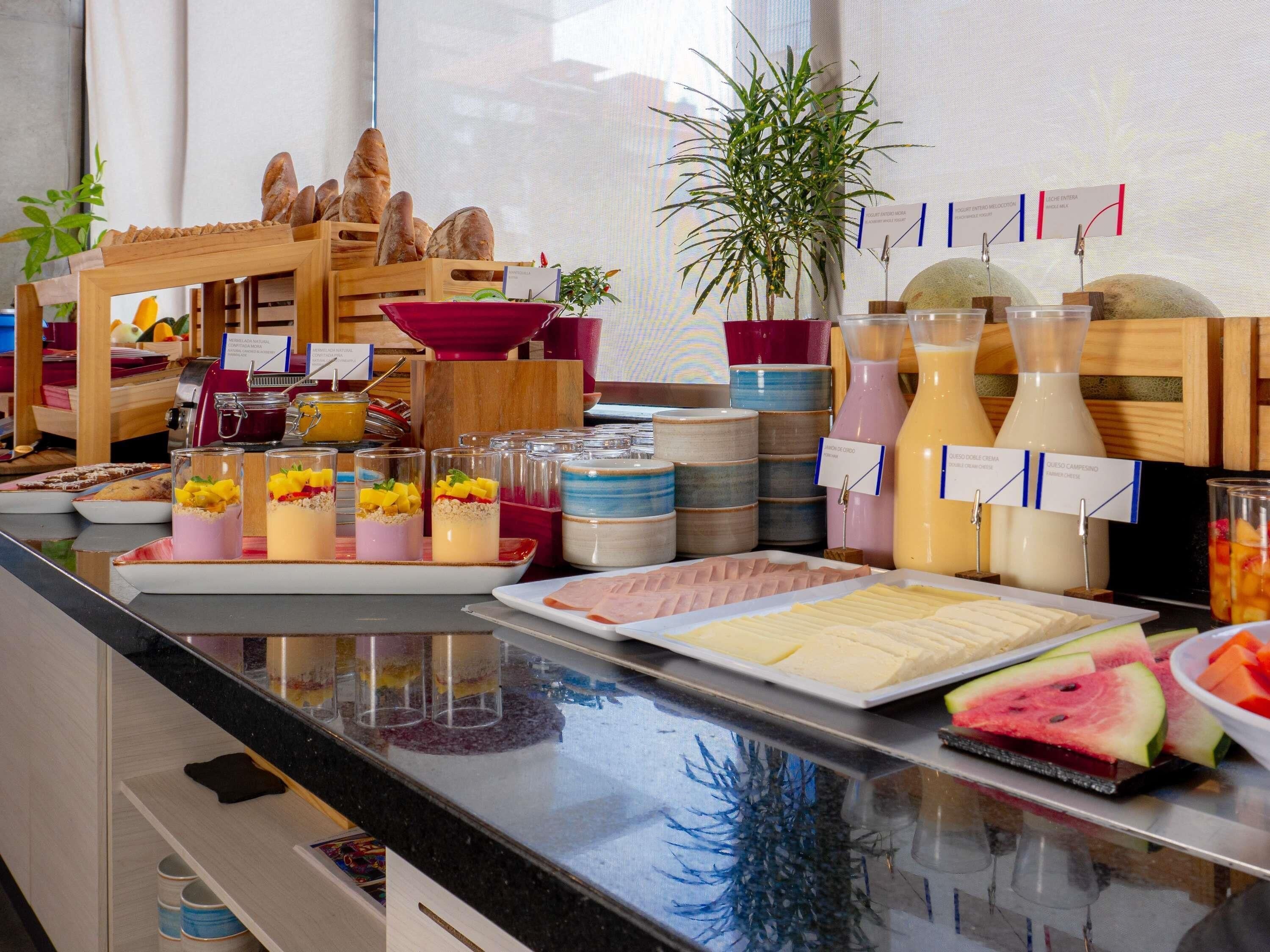 Un buffet proposant une variété de plats et de boissons, notamment des fruits, des desserts et du fromage.