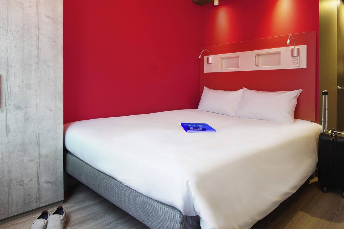 Ein Hotelzimmer mit einem großen Bett, roten Wänden und einem Holzboden.