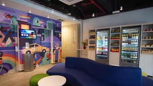 A colorful interior with a blue sofa, green and yellow stools, and a refrigerator stocked with beverages. - ibis Budget Bogota Marly (Bogotá)