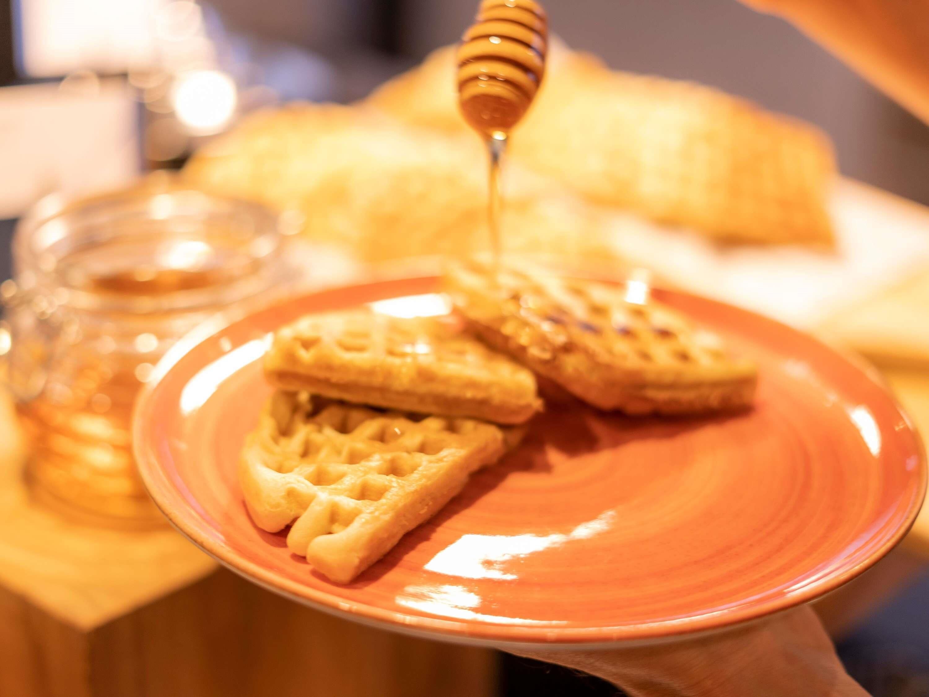 Une assiette avec des gaufres et du miel versé dessus.