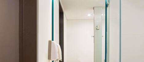 A modern bathroom with a white sink, a mirror with a teal frame, and a glass shower enclosure.