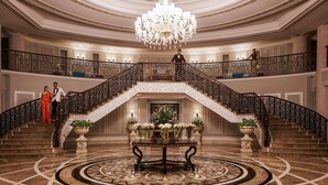 A grand lobby with a central staircase, ornate ceiling, and chandeliers. - Raffles Udaipur (Udaipur)