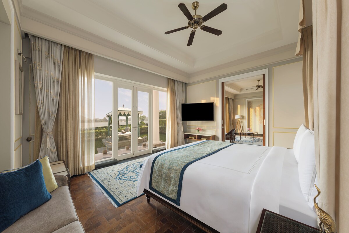 A hotel room with a large bed, a ceiling fan, a flat-screen TV, and a view of the outdoors.