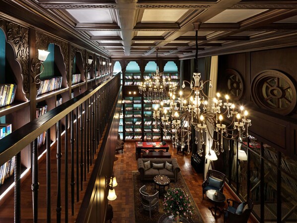 Une bibliothèque avec des étagères, un lustre et un espace salon.