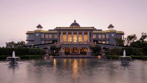 A grand building with a central dome, symmetrical columns, and a well-maintained garden with fountains. - Raffles Udaipur (Udaipur)