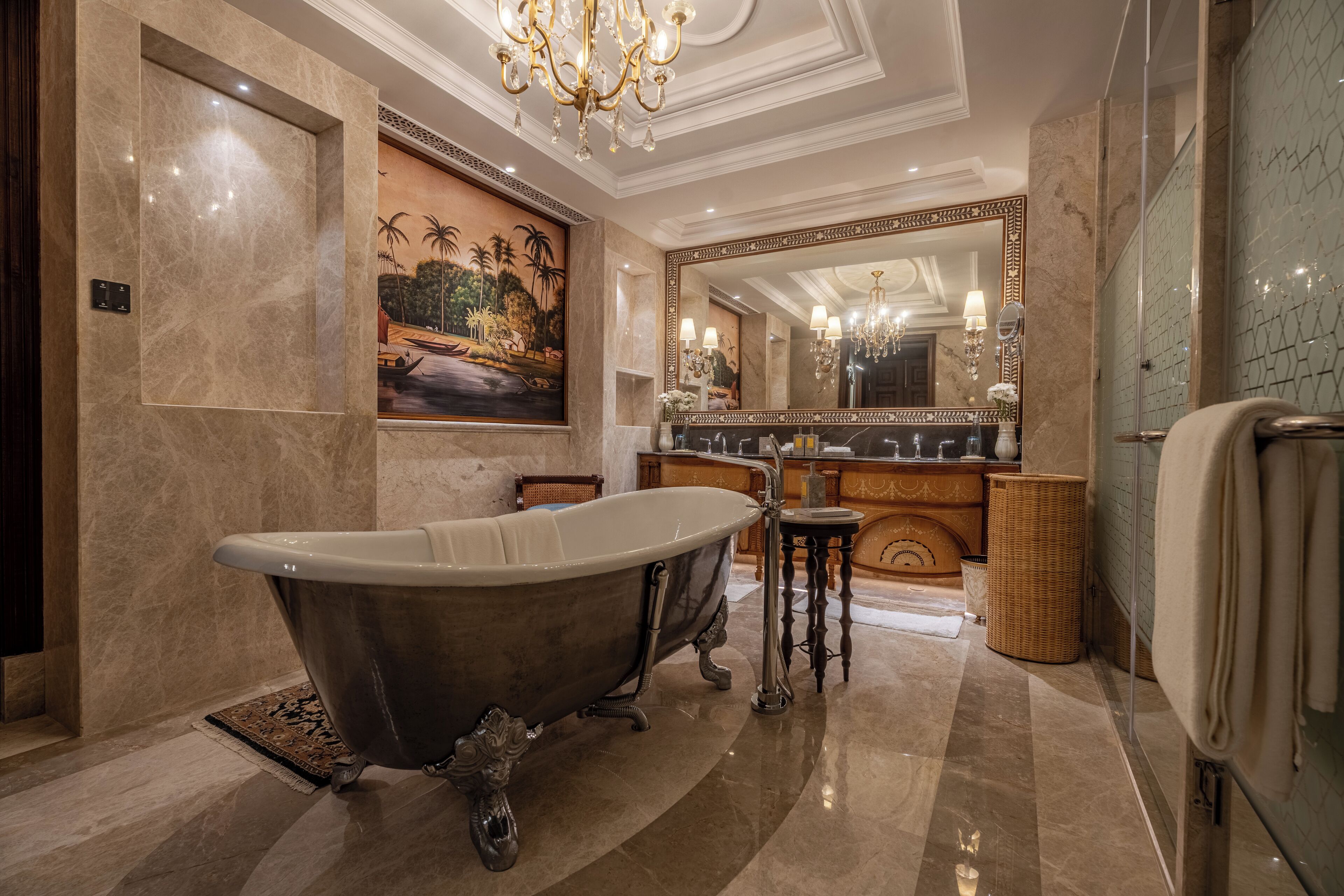 A luxurious bathroom with a clawfoot bathtub, a large mirror, and a chandelier.
