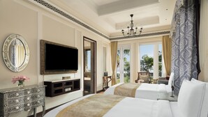 A hotel room with two beds, a television, a decorative mirror, and a view of the outdoors. - Raffles Udaipur (Udaipur)