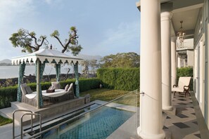 A pool area with a gazebo, a chair, and a view of the water. - Raffles Udaipur (Udaipur)