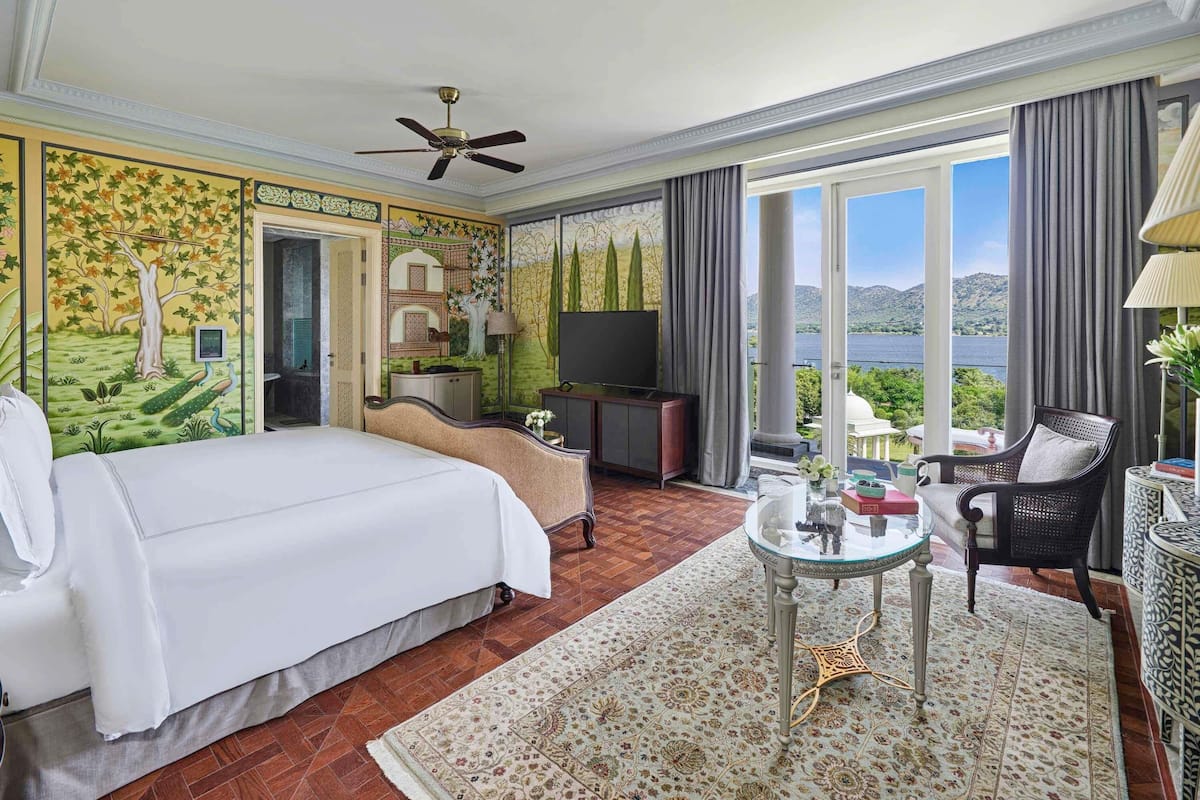 A hotel room with a bed, a television, a desk, a chair, and a view of the outdoors.