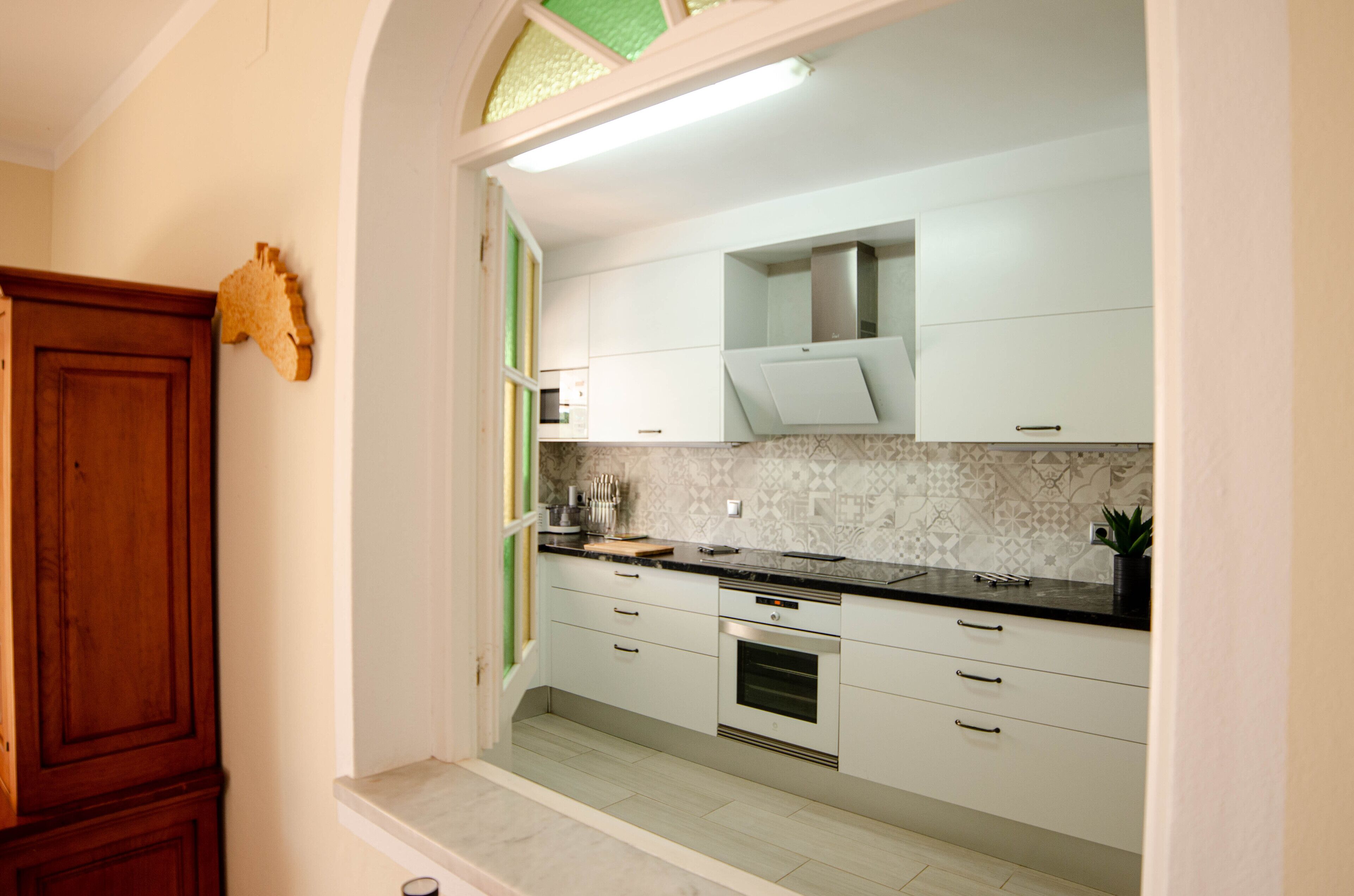 A modern kitchen with white cabinets, a black countertop, and a built-in oven.
