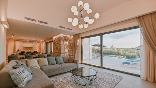 A modern living room with a sectional sofa, a glass coffee table, and a stone accent wall. - Gorgeous Villa Luana with wellness and pool (Malinska)