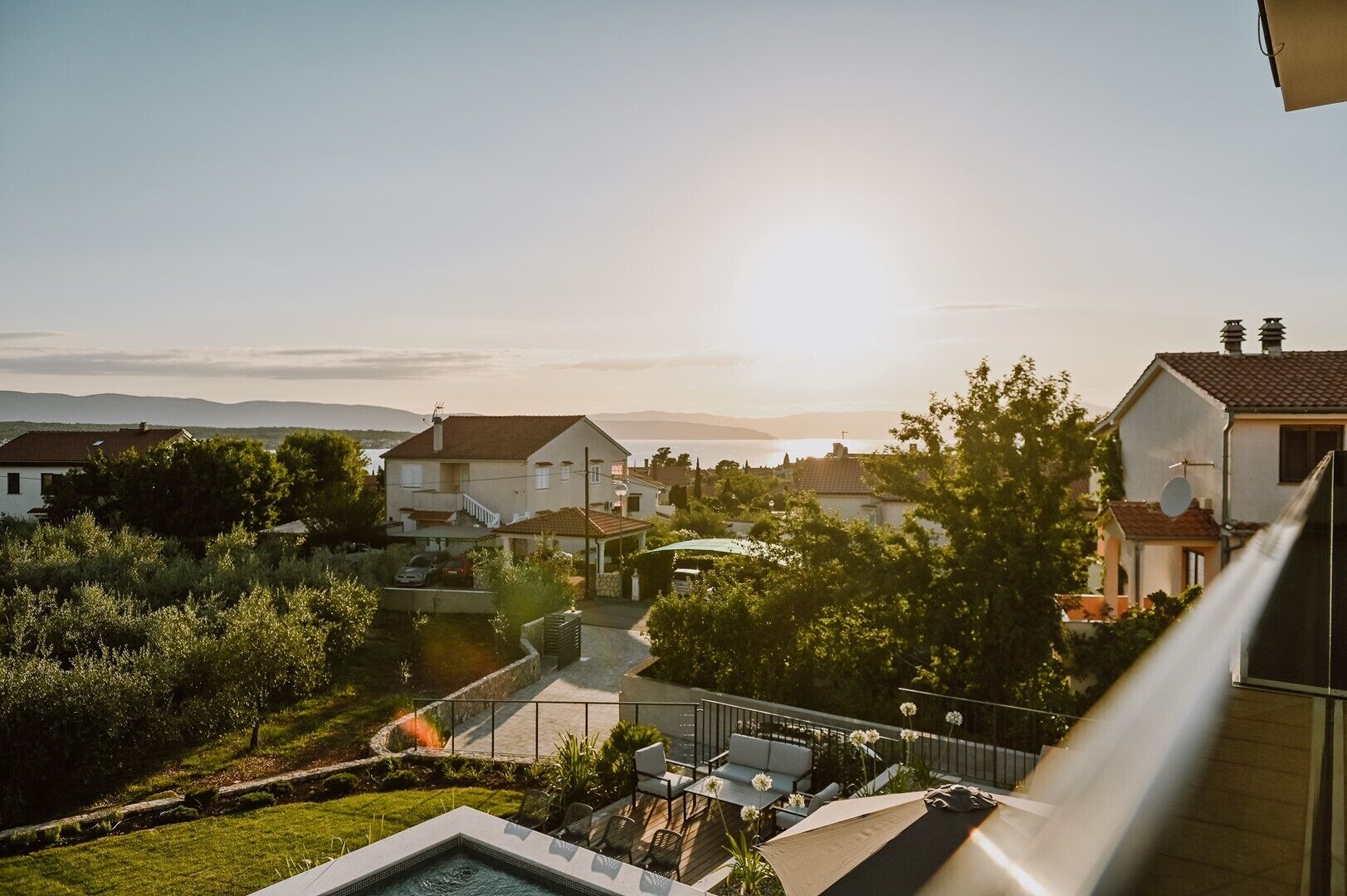 A residential area with houses, a swimming pool, and a clear view of the sea.