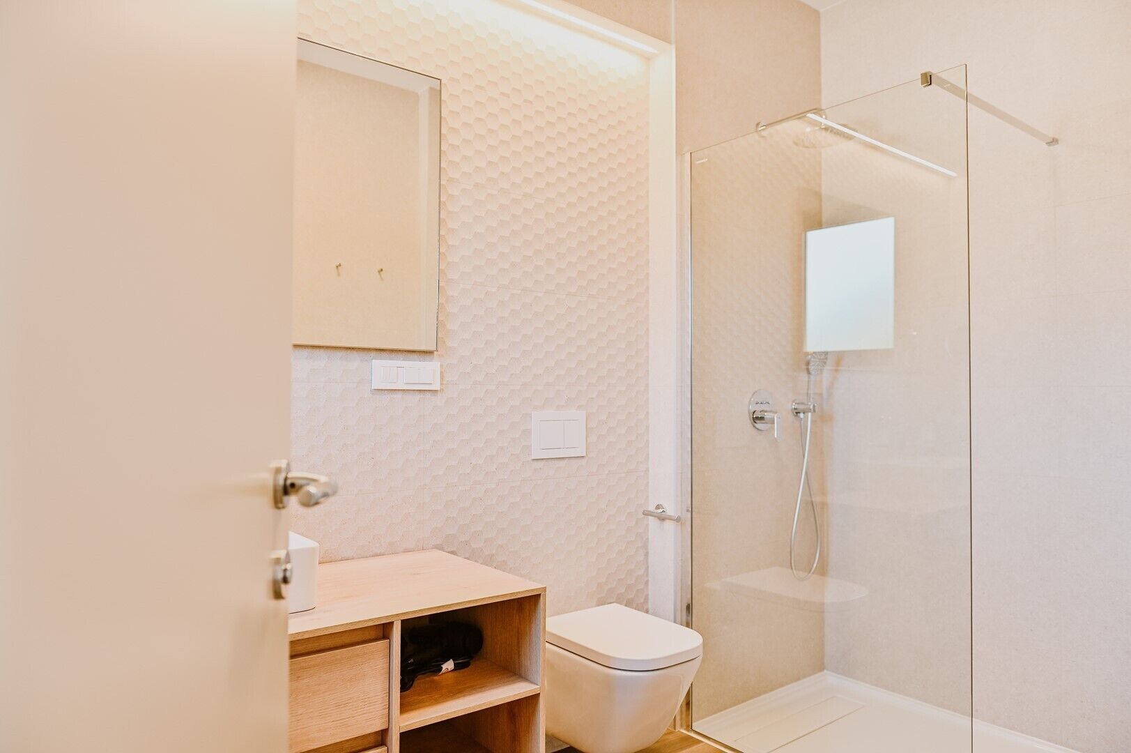 A modern bathroom with a glass shower enclosure, a wooden vanity, and a toilet.