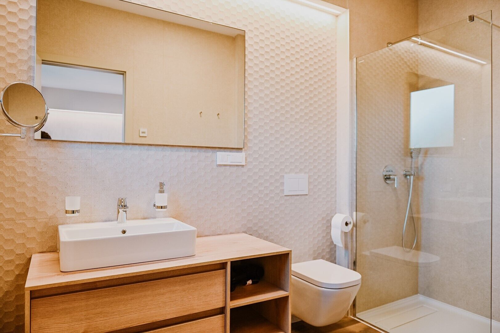 A modern bathroom with a large mirror, a sink, a toilet, and a glass shower enclosure.
