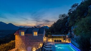 A stone house with a swimming pool, outdoor seating, and a view of mountains. - Stone villa Judita with heated pool and hydro-massage, Billiard Room (Makarska)