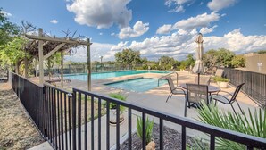 Un patio trasero con piscina, mobiliario de jardín y una pérgola.