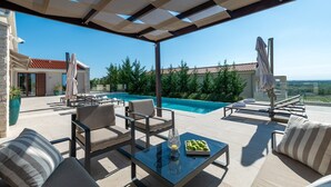 Una terraza en la azotea con piscina, mobiliario exterior y vistas al paisaje.
