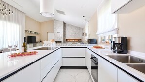 Cocina moderna con isla central, muebles blancos y salpicadero de mármol.