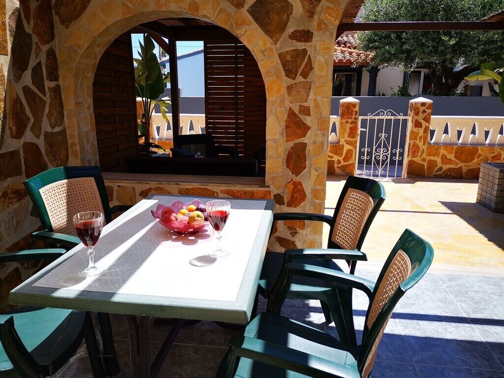 Un patio al aire libre con un arco de piedra, una mesa con sillas y un frutero.